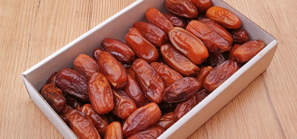 A box of deglet nour dates on a wooden table